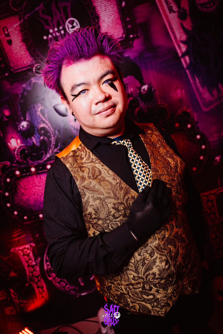 Rapaz de cabelo roxo e colete dourado faz pose — Sad Baile Joker, Halloween em São Paulo, 17/10/2026