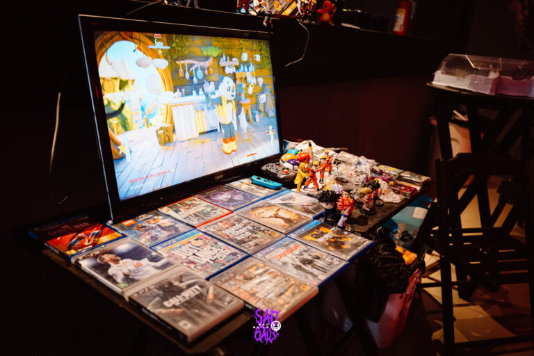 Estande de videogame com tela e cartas colecionáveis — Sad Baile Joker, Halloween em São Paulo, 17/10/2026