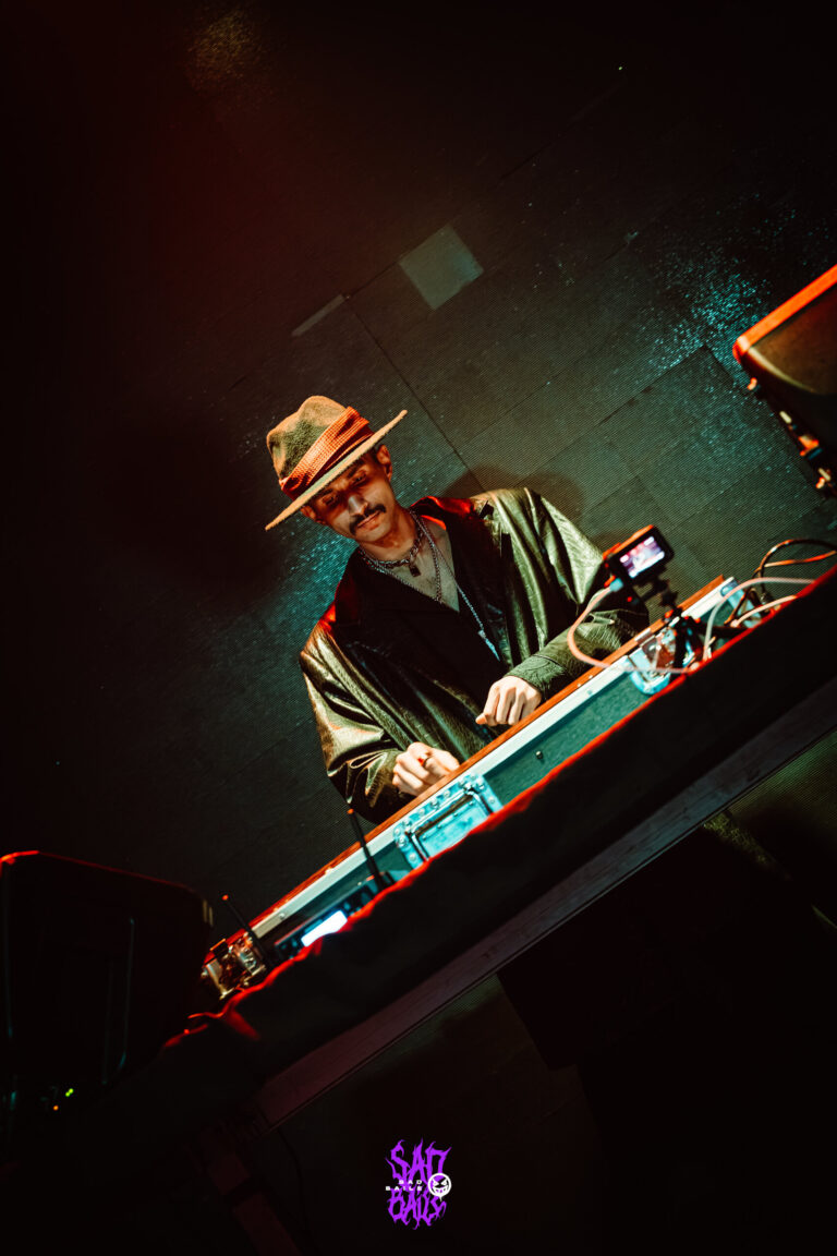 DJ de chapéu toca sob luz verde — Sad Baile Joker, Halloween em São Paulo, 17/10/2026