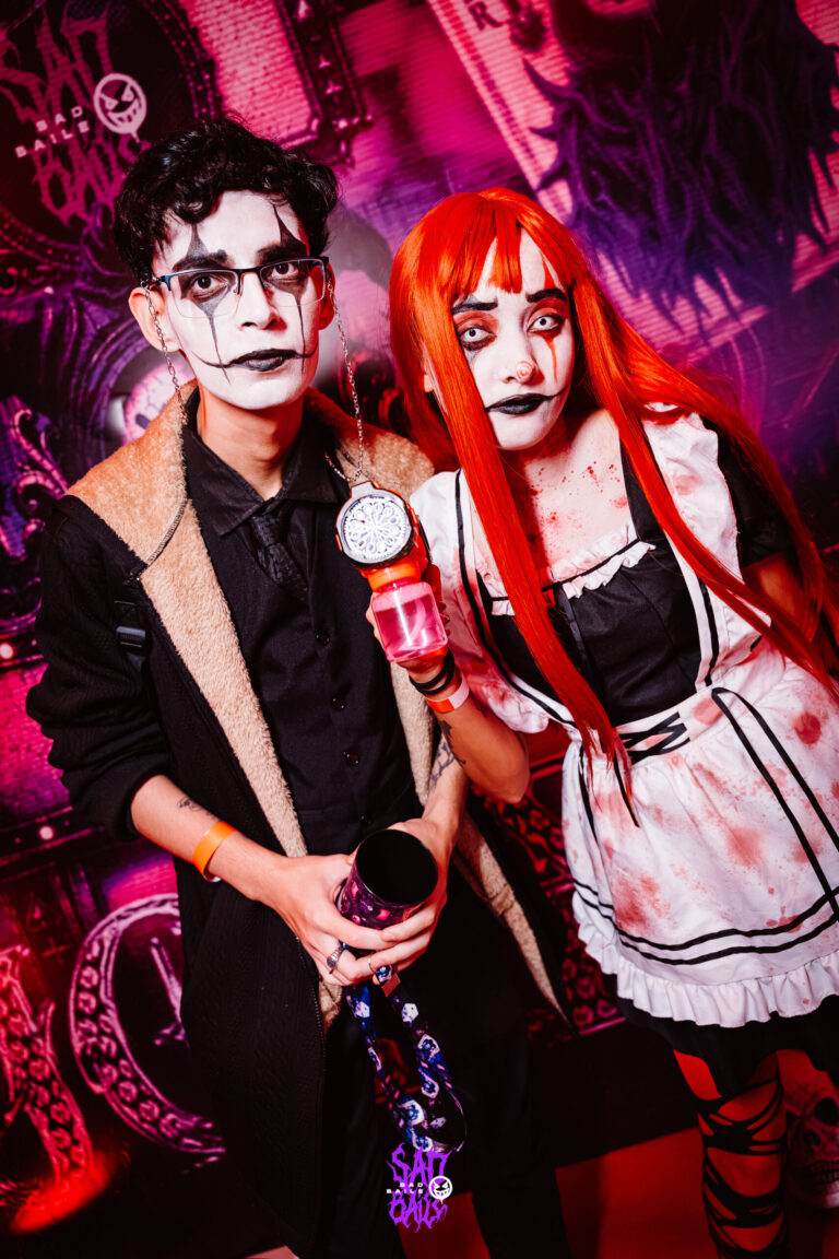 Casal com maquiagem branca, ela de peruca ruiva e avental — Sad Baile Joker, Halloween em São Paulo, 17/10/2026