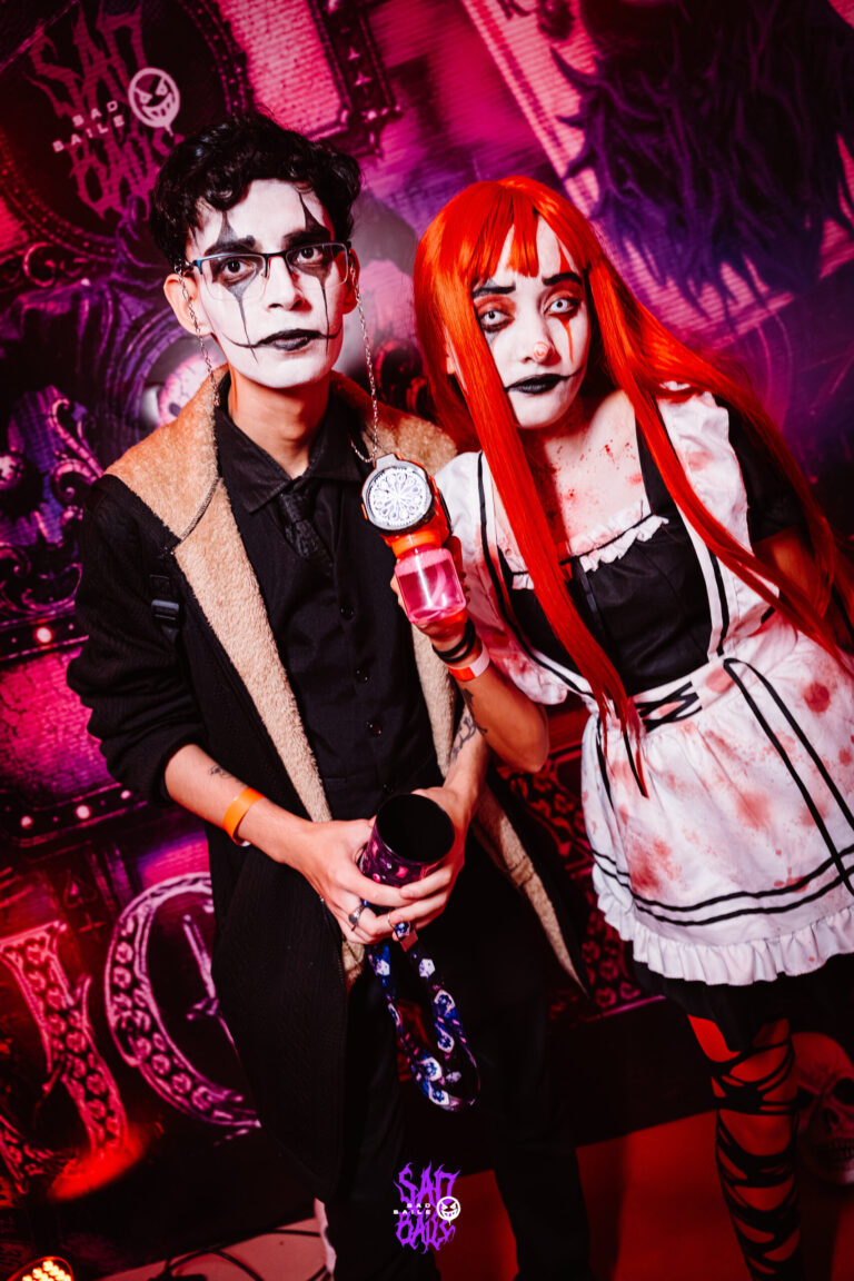 Casal fantasiado segura copos da edição Joker — Sad Baile Joker, Halloween em São Paulo, 17/10/2026
