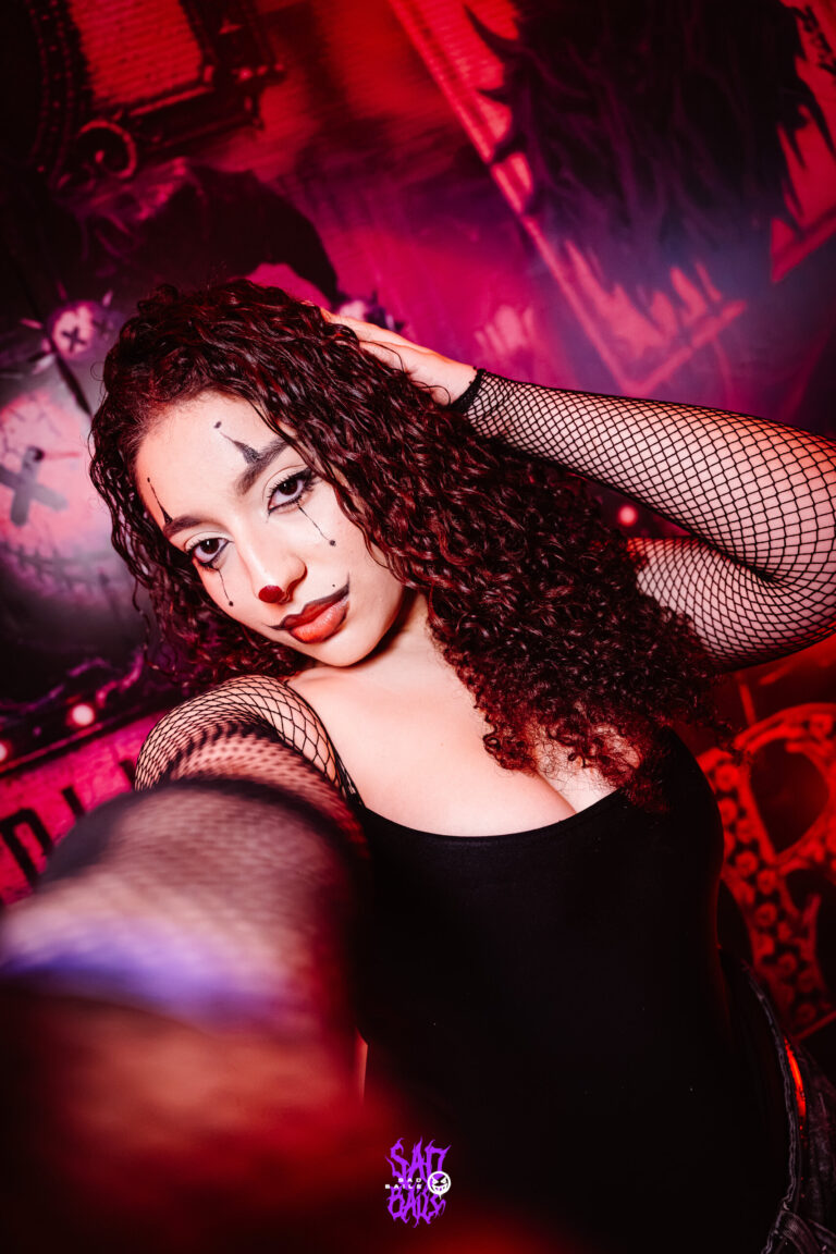 Garota de cabelo cacheado sob luz vermelha — Sad Baile Joker, Halloween em São Paulo, 17/10/2026