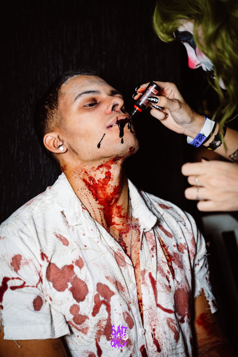 Maquiadora aplica sangue falso no rosto de um rapaz — Sad Baile Joker, Halloween em São Paulo, 17/10/2026