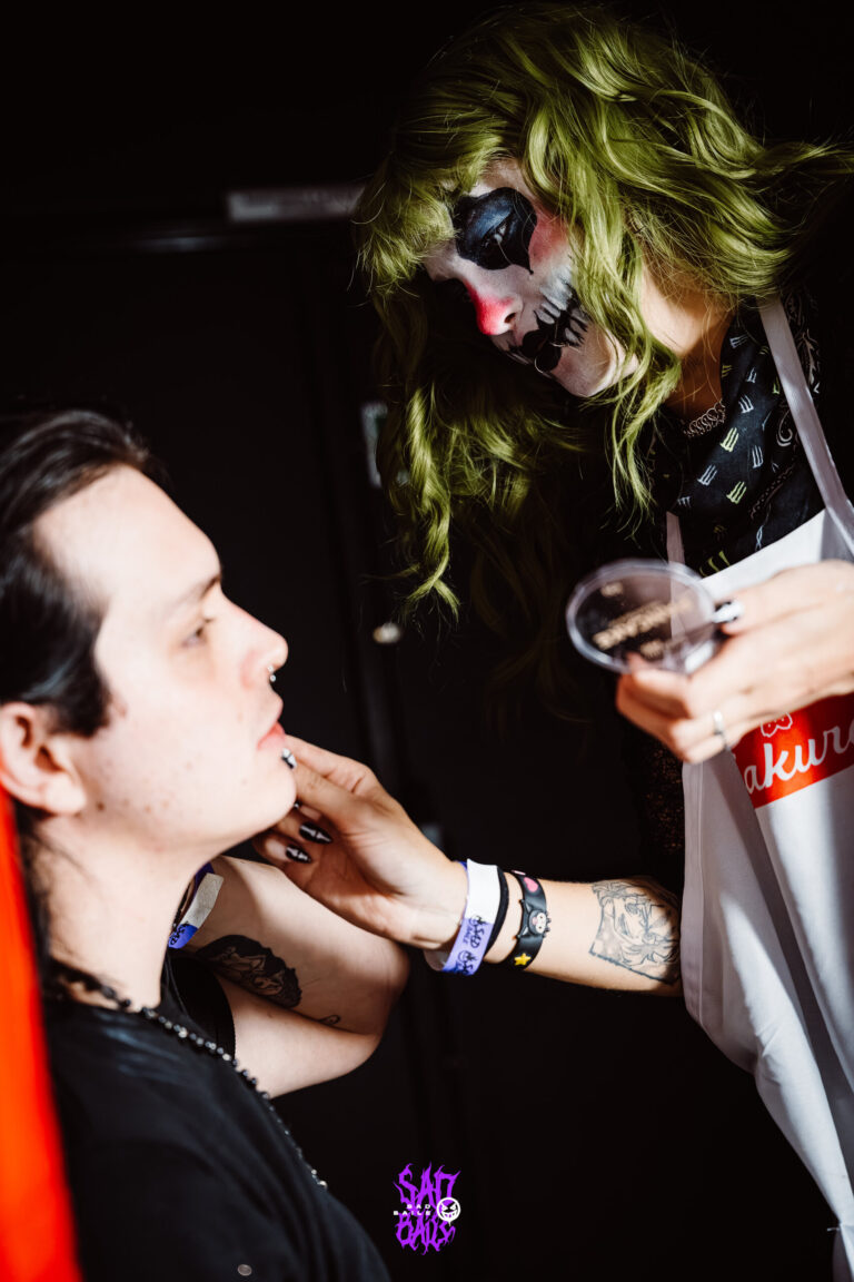 Maquiadora finaliza a pintura facial de um rapaz — Sad Baile Joker, Halloween em São Paulo, 17/10/2026