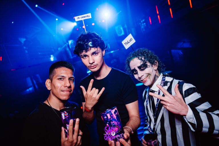 Três amigos posam na pista sob luz azul — Sad Baile Joker, Halloween em São Paulo, 17/10/2026