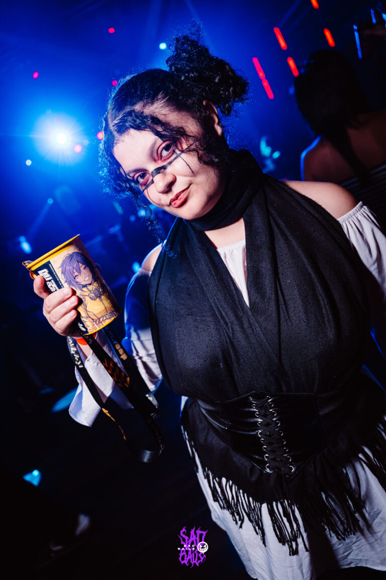 Garota de óculos e corset preto sob luz azul — Sad Baile Joker, Halloween em São Paulo, 17/10/2026