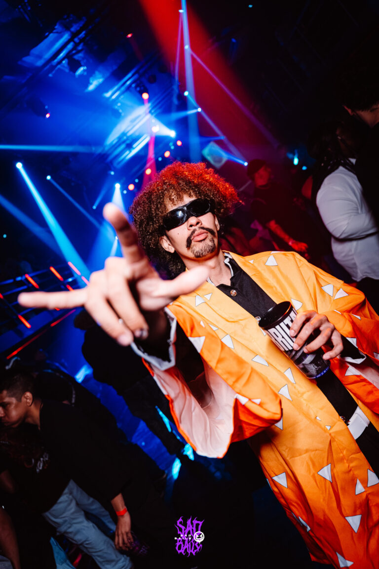 Rapaz de kimono laranja faz pose na pista — Sad Baile Joker, Halloween em São Paulo, 17/10/2026
