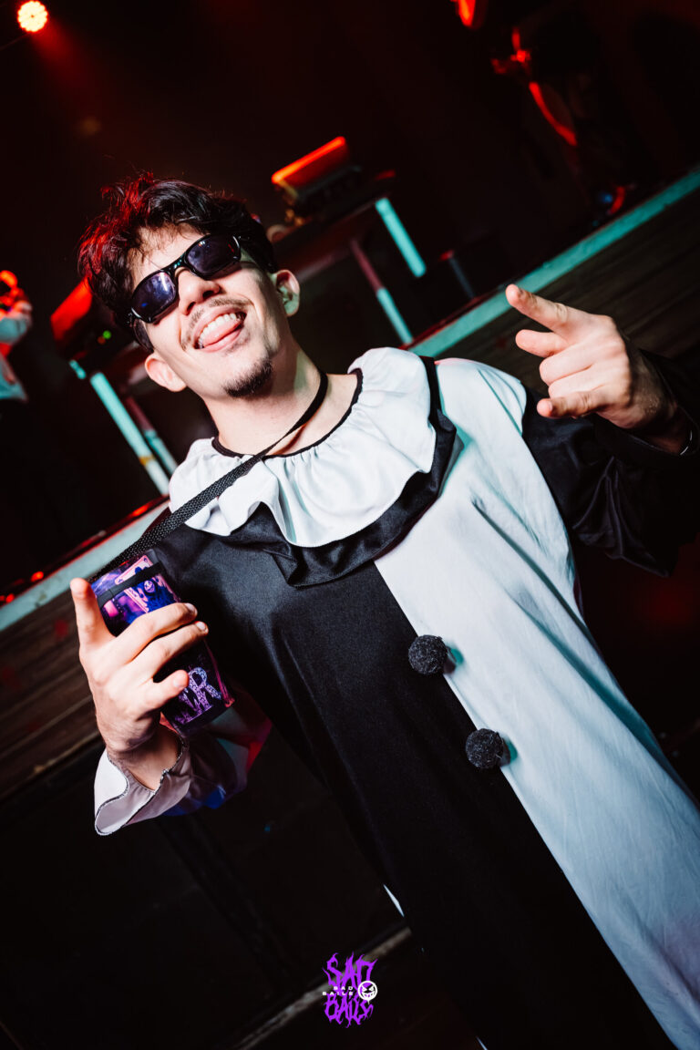 Rapaz de óculos escuros e roupa de palhaço com copo Joker — Sad Baile Joker, Halloween em São Paulo, 17/10/2026