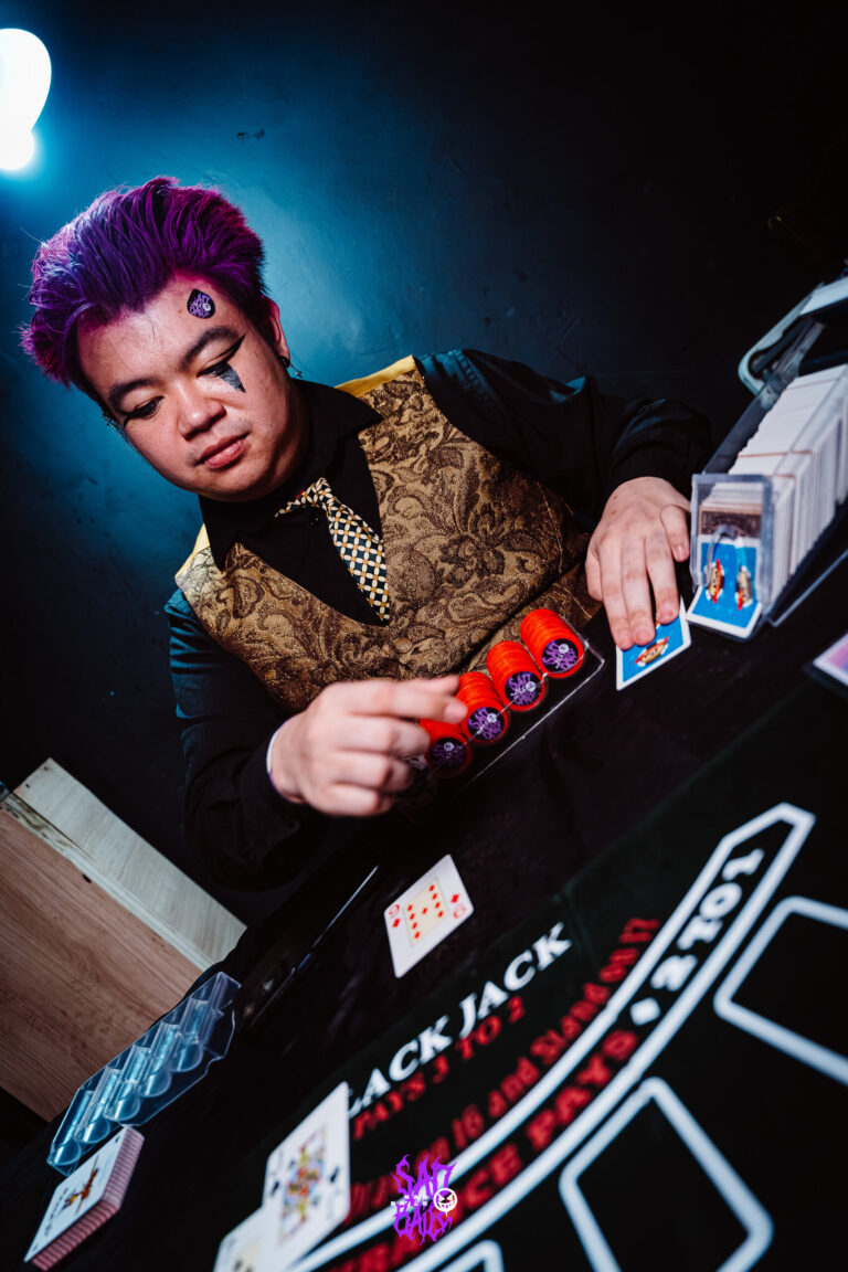Crupiê de cabelo roxo distribui cartas no blackjack — Sad Baile Joker, Halloween em São Paulo, 17/10/2026