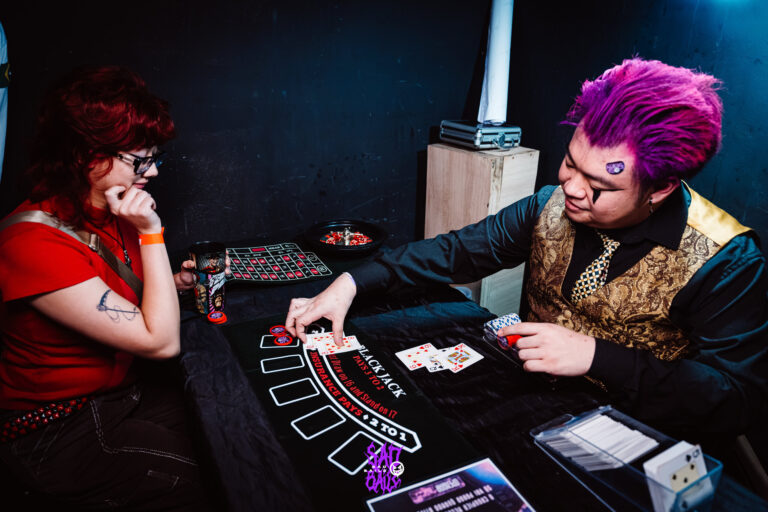 Jogadoras na mesa de blackjack com o crupiê — Sad Baile Joker, Halloween em São Paulo, 17/10/2026