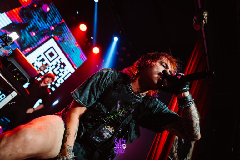 Artista canta agachado no palco com o QR code no telão — Sad Baile Joker, Halloween em São Paulo, 17/10/2026