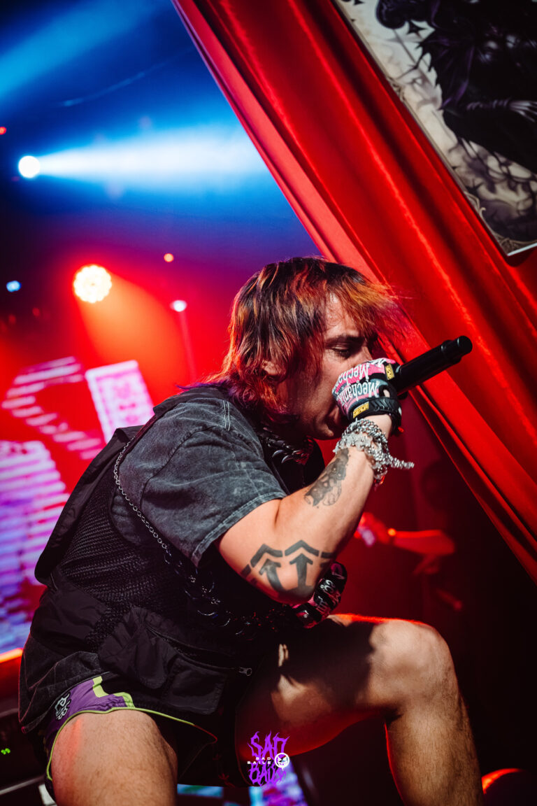 Artista canta entre cortinas vermelhas — Sad Baile Joker, Halloween em São Paulo, 17/10/2026