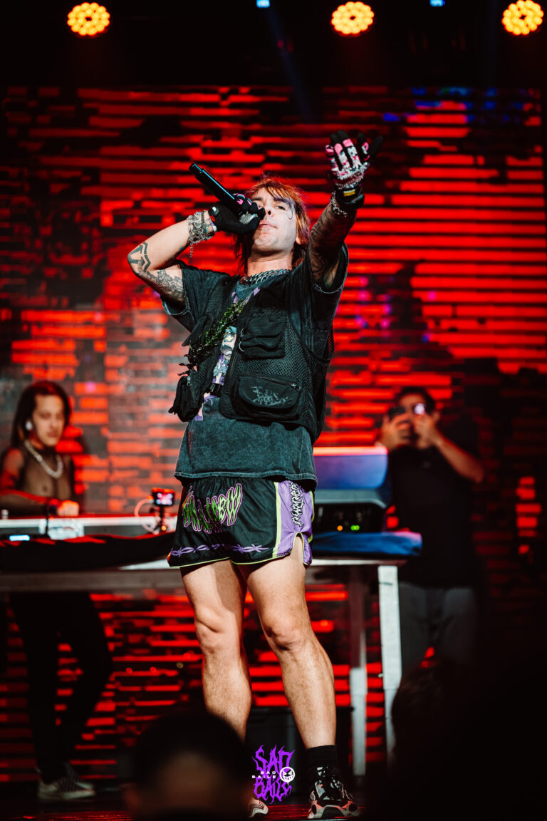 Artista ergue a mão diante do telão vermelho — Sad Baile Joker, Halloween em São Paulo, 17/10/2026