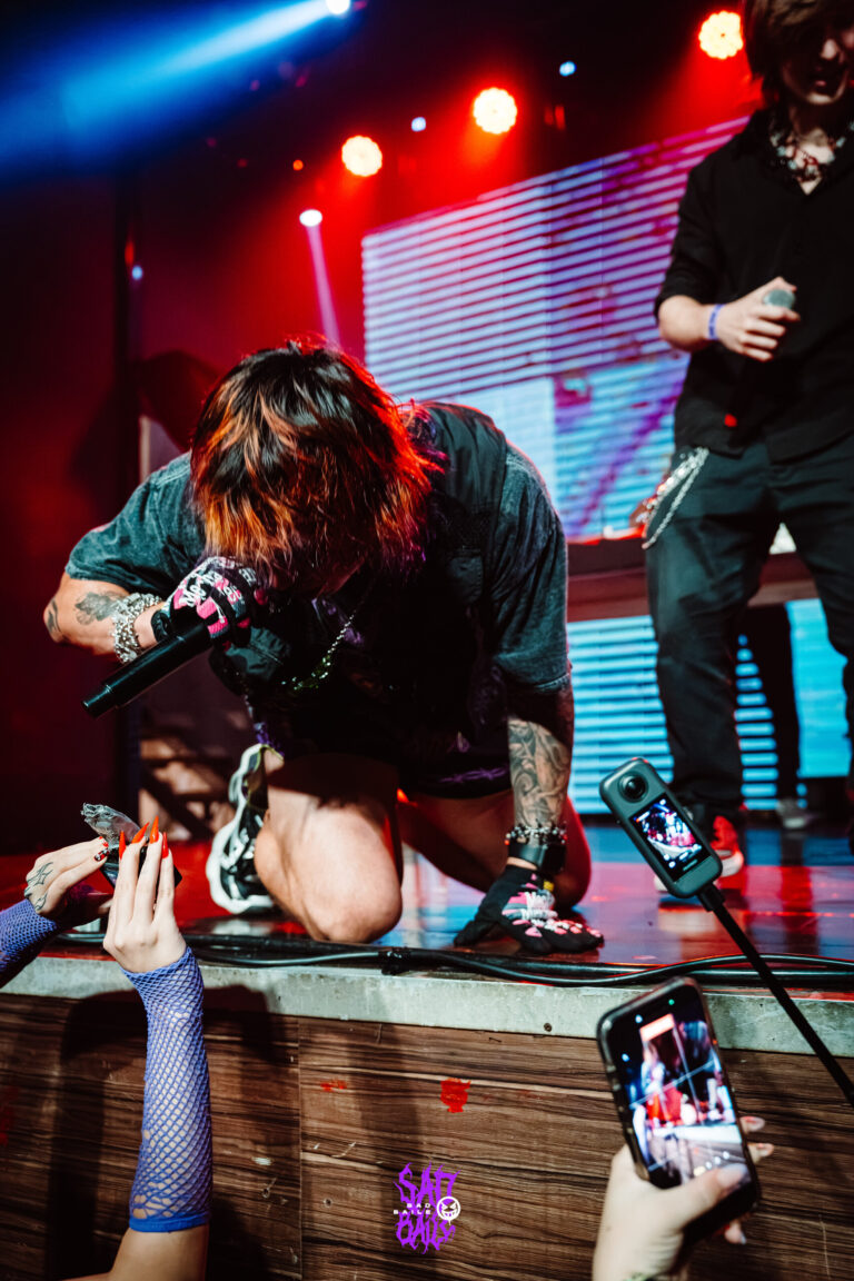 Artista ajoelhado no palco com fã filmando — Sad Baile Joker, Halloween em São Paulo, 17/10/2026
