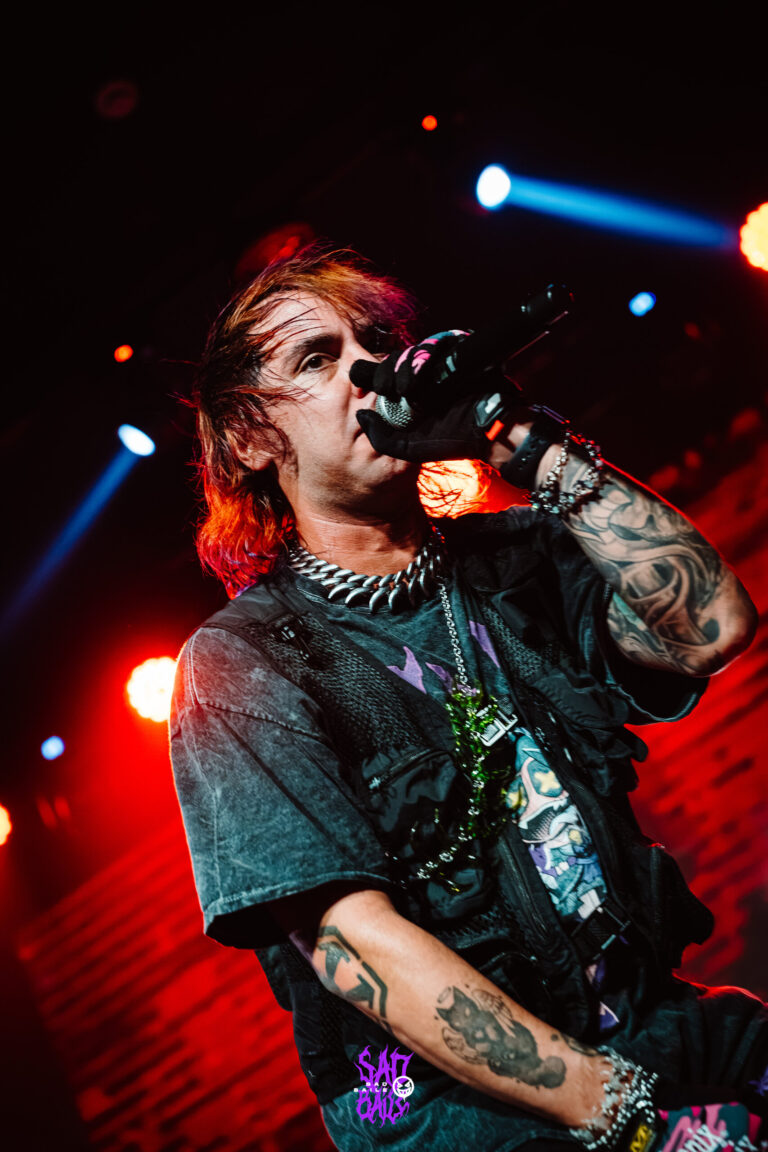 Artista tatuado de colete canta sob luz vermelha — Sad Baile Joker, Halloween em São Paulo, 17/10/2026