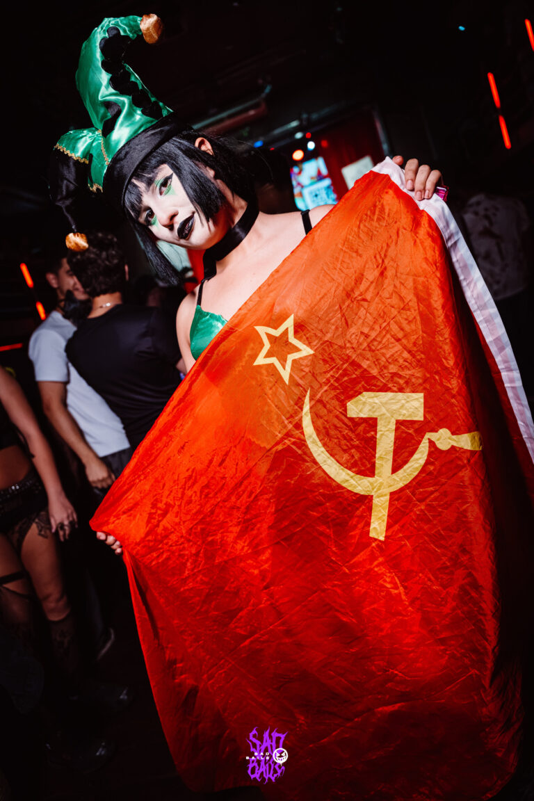 Garota de chapéu de bobo da corte com bandeira vermelha — Sad Baile Joker, Halloween em São Paulo, 17/10/2026