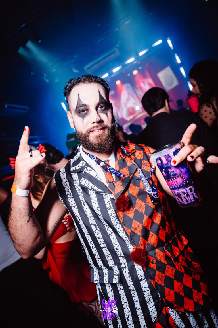 Palhaço de barba e roupa xadrez vermelha faz sinal de rock — Sad Baile Joker, Halloween em São Paulo, 17/10/2026