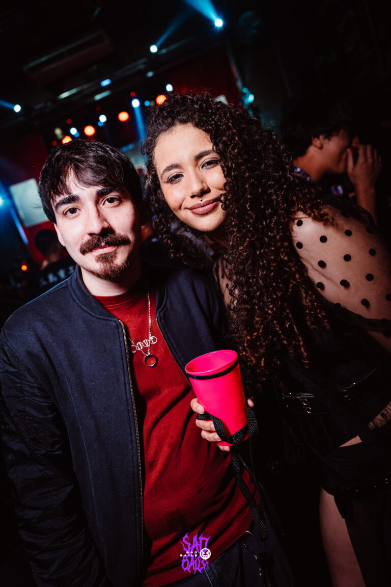 Casal sorri na pista com copo vermelho — Sad Baile Joker, Halloween em São Paulo, 17/10/2026