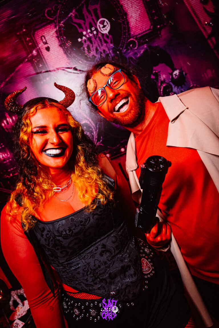 Diaba de chifres sorri com amigo pintado de vermelho — Sad Baile Joker, Halloween em São Paulo, 17/10/2026