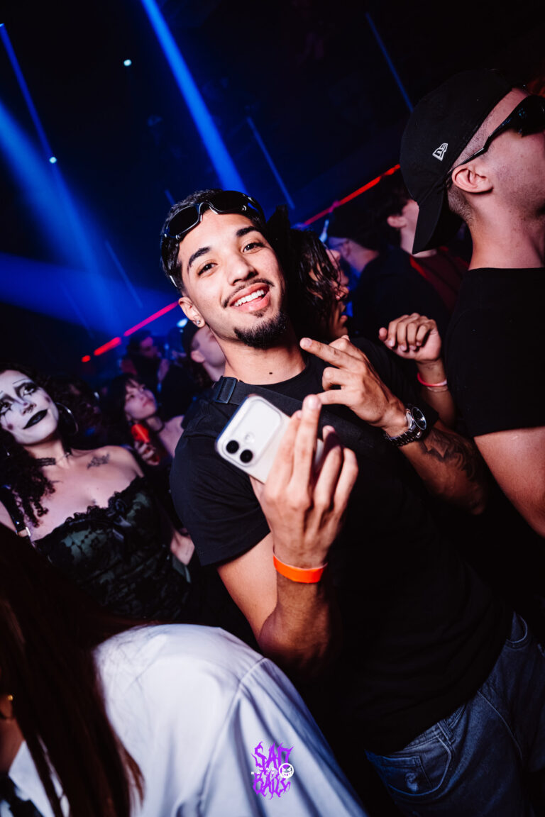Rapaz segura o celular na pista lotada — Sad Baile Joker, Halloween em São Paulo, 17/10/2026