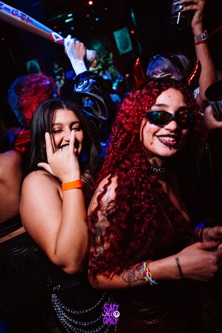 Amigas de cabelo ruivo e óculos escuros sorriem — Sad Baile Joker, Halloween em São Paulo, 17/10/2026