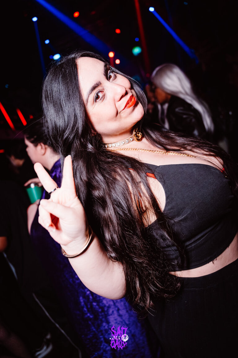 Garota faz sinal de paz sob luz azul — Sad Baile Joker, Halloween em São Paulo, 17/10/2026