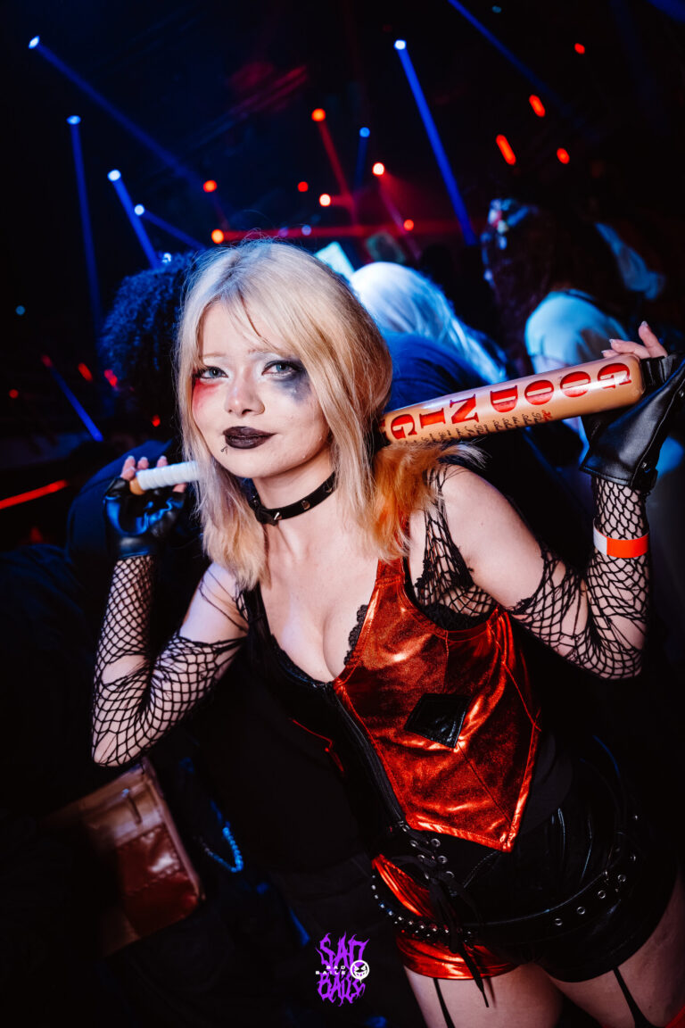 Fantasia de Arlequina com taco sob luz azul — Sad Baile Joker, Halloween em São Paulo, 17/10/2026