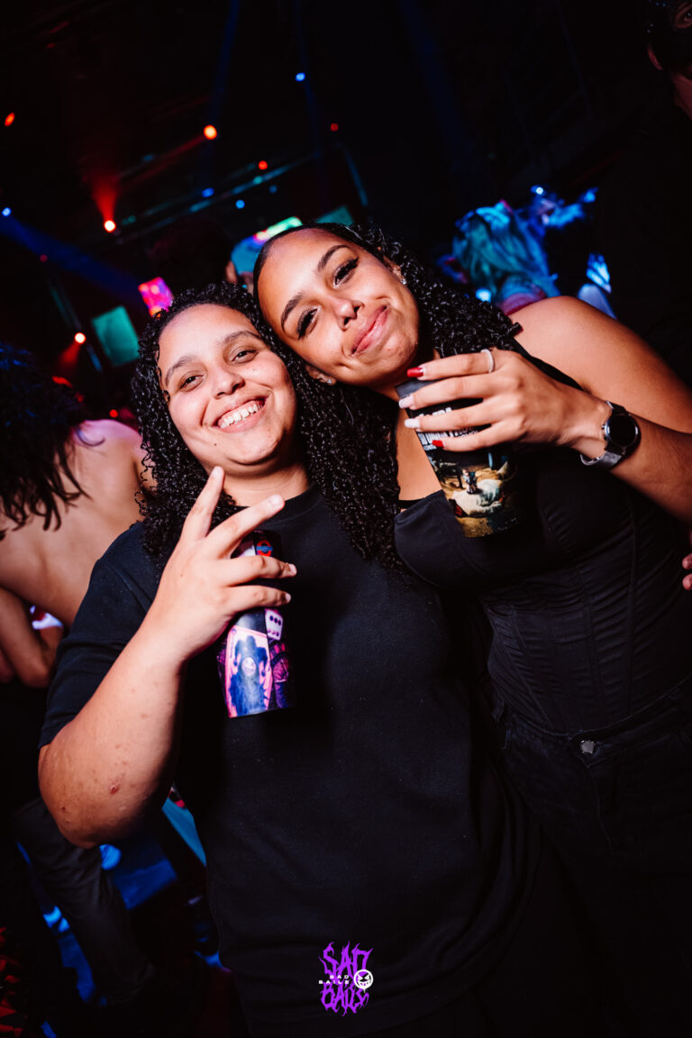 Duas amigas sorriem com copos — Sad Baile Joker, Halloween em São Paulo, 17/10/2026