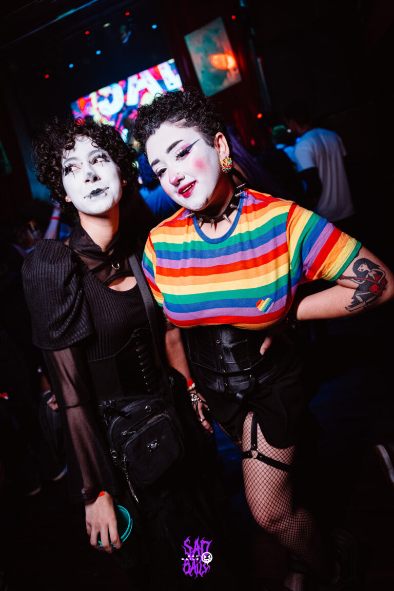 Amigas de rosto pintado de branco, uma de blusa arco-íris — Sad Baile Joker, Halloween em São Paulo, 17/10/2026
