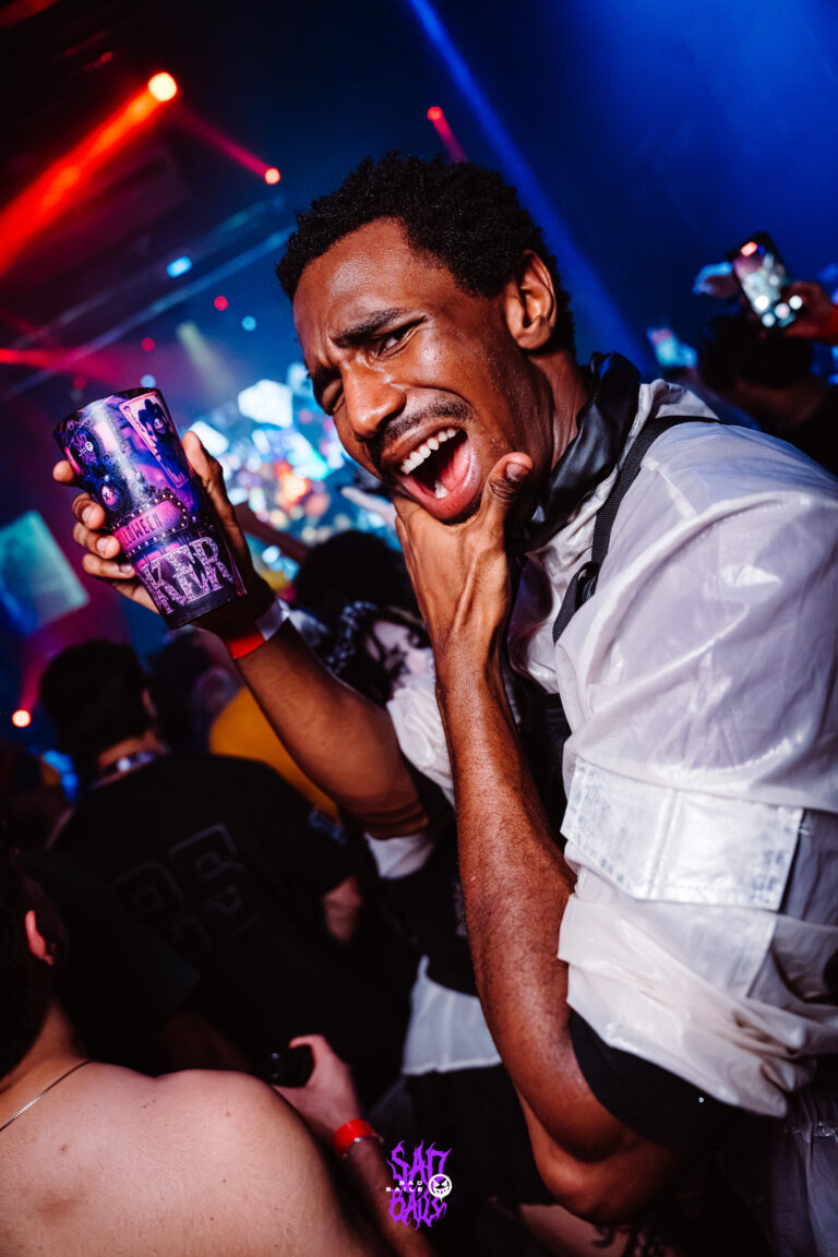 Rapaz de camisa branca brinca com copo Joker — Sad Baile Joker, Halloween em São Paulo, 17/10/2026