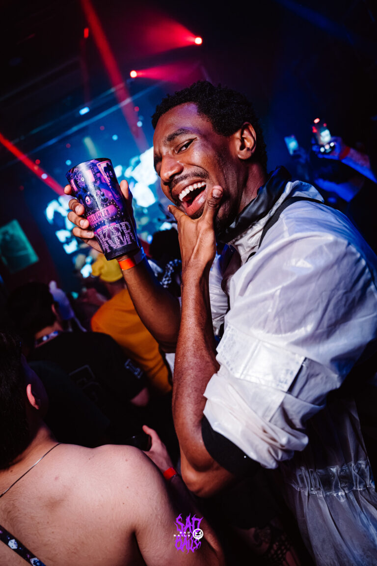 Rapaz de camisa branca sorri com copo Joker — Sad Baile Joker, Halloween em São Paulo, 17/10/2026