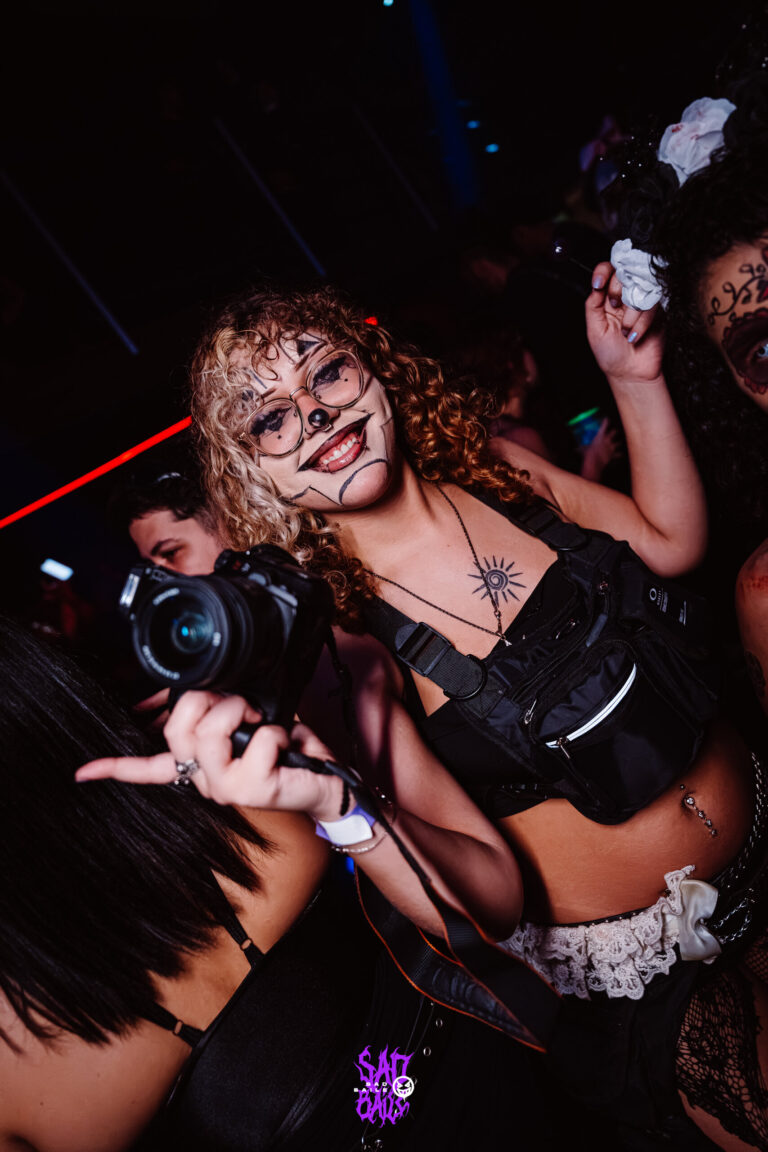 Garota com câmera e maquiagem de onça na pista — Sad Baile Joker, Halloween em São Paulo, 17/10/2026