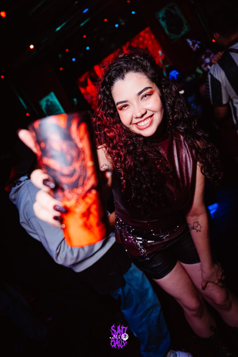 Garota de cabelo cacheado sorri com copo — Sad Baile Joker, Halloween em São Paulo, 17/10/2026