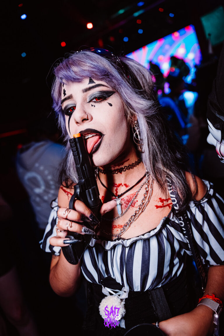 Garota de peruca lilás com arma de brinquedo — Sad Baile Joker, Halloween em São Paulo, 17/10/2026