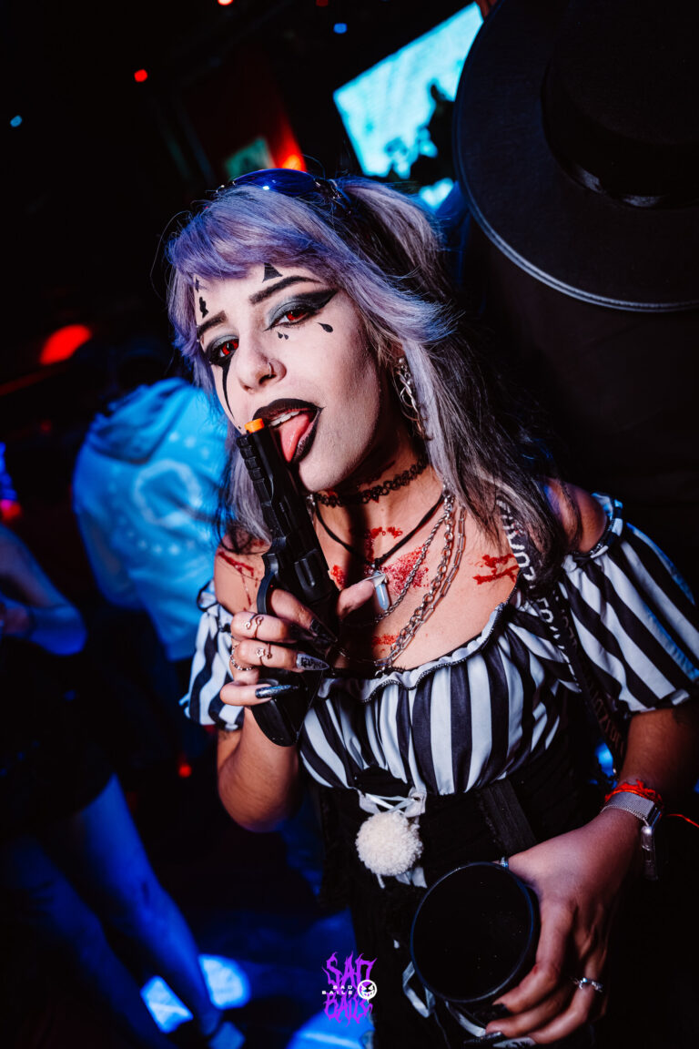 Palhaça de peruca lilás e blusa listrada com arma de brinquedo — Sad Baile Joker, Halloween em São Paulo, 17/10/2026