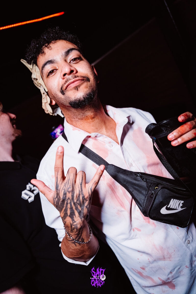 Rapaz de camisa branca e pochete faz pose — Sad Baile Joker, Halloween em São Paulo, 17/10/2026