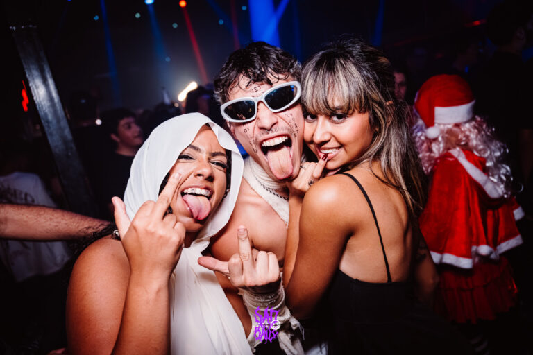 Amigos mostram a língua com Papai Noel ao fundo — Sad Baile Joker, Halloween em São Paulo, 17/10/2026