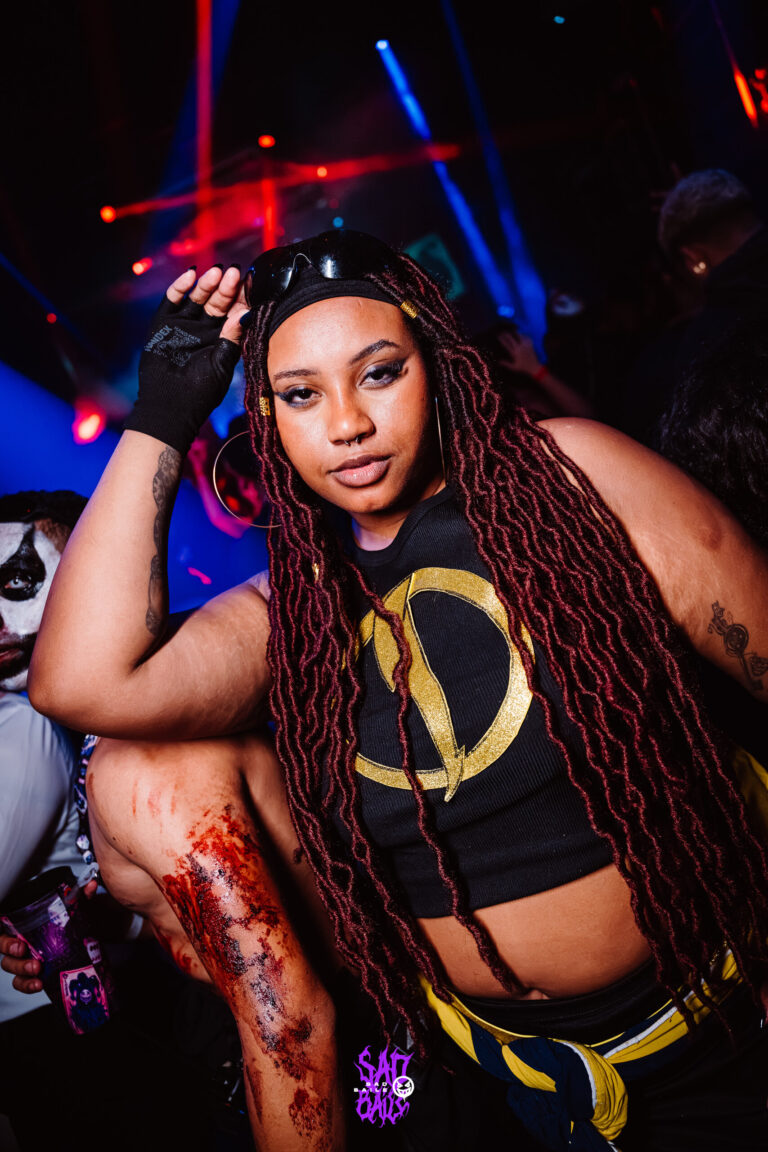 Garota de tranças e top com símbolo dourado — Sad Baile Joker, Halloween em São Paulo, 17/10/2026