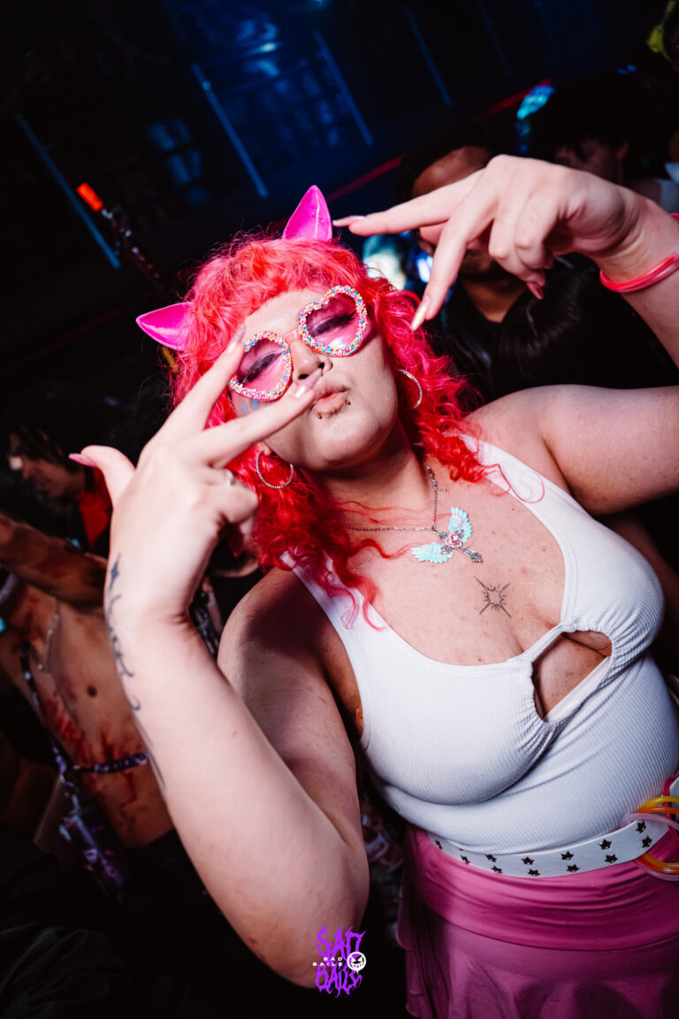 Garota de peruca rosa e orelhas faz sinal com as mãos — Sad Baile Joker, Halloween em São Paulo, 17/10/2026