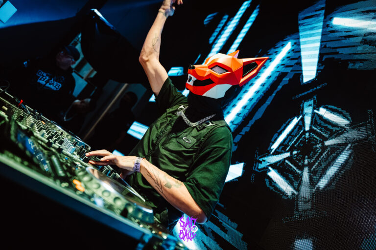 DJ mascarado de raposa ergue o braço — Sad Baile Joker, Halloween em São Paulo, 17/10/2026