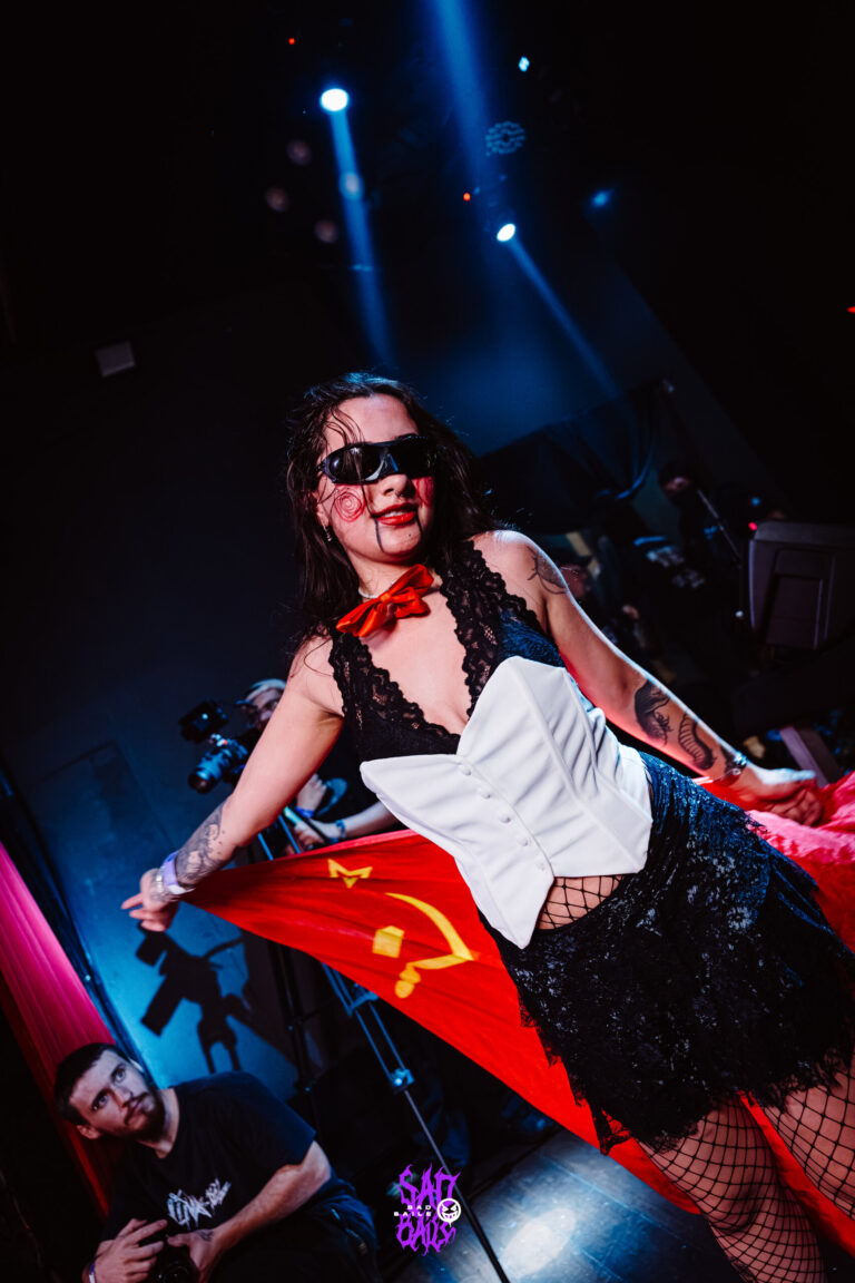 Garota com bandeira vermelha dança no palco — Sad Baile Joker, Halloween em São Paulo, 17/10/2026