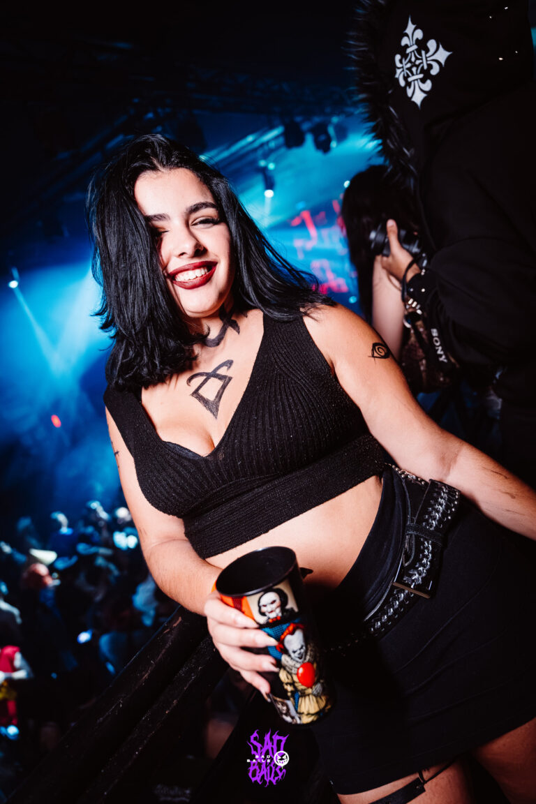 Garota de top preto sorri com copo na pista — Sad Baile Joker, Halloween em São Paulo, 17/10/2026