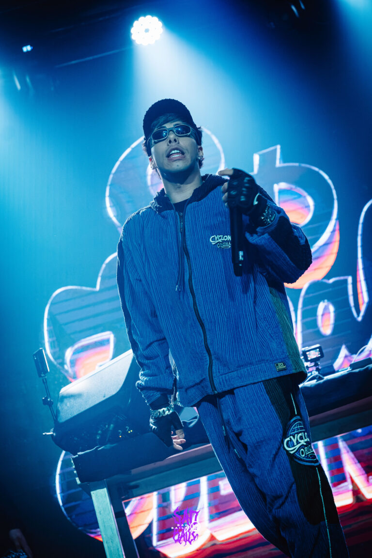 Rapper de boné canta sob canhão de luz azul — Sad Baile Joker, Halloween em São Paulo, 17/10/2026
