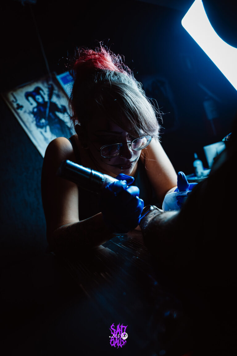 Tatuadora de luvas azuis concentrada — Sad Baile Joker, Halloween em São Paulo, 17/10/2026