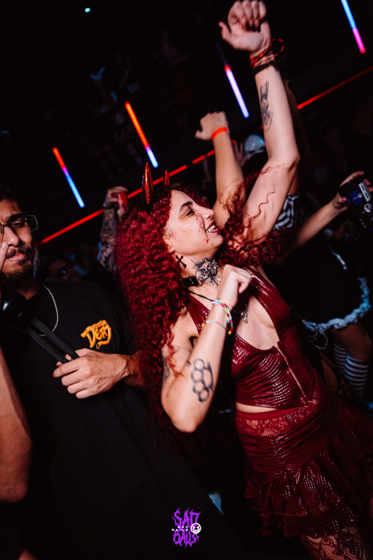 Garota de cabelo ruivo cacheado dança com o braço erguido — Sad Baile Joker, Halloween em São Paulo, 17/10/2026