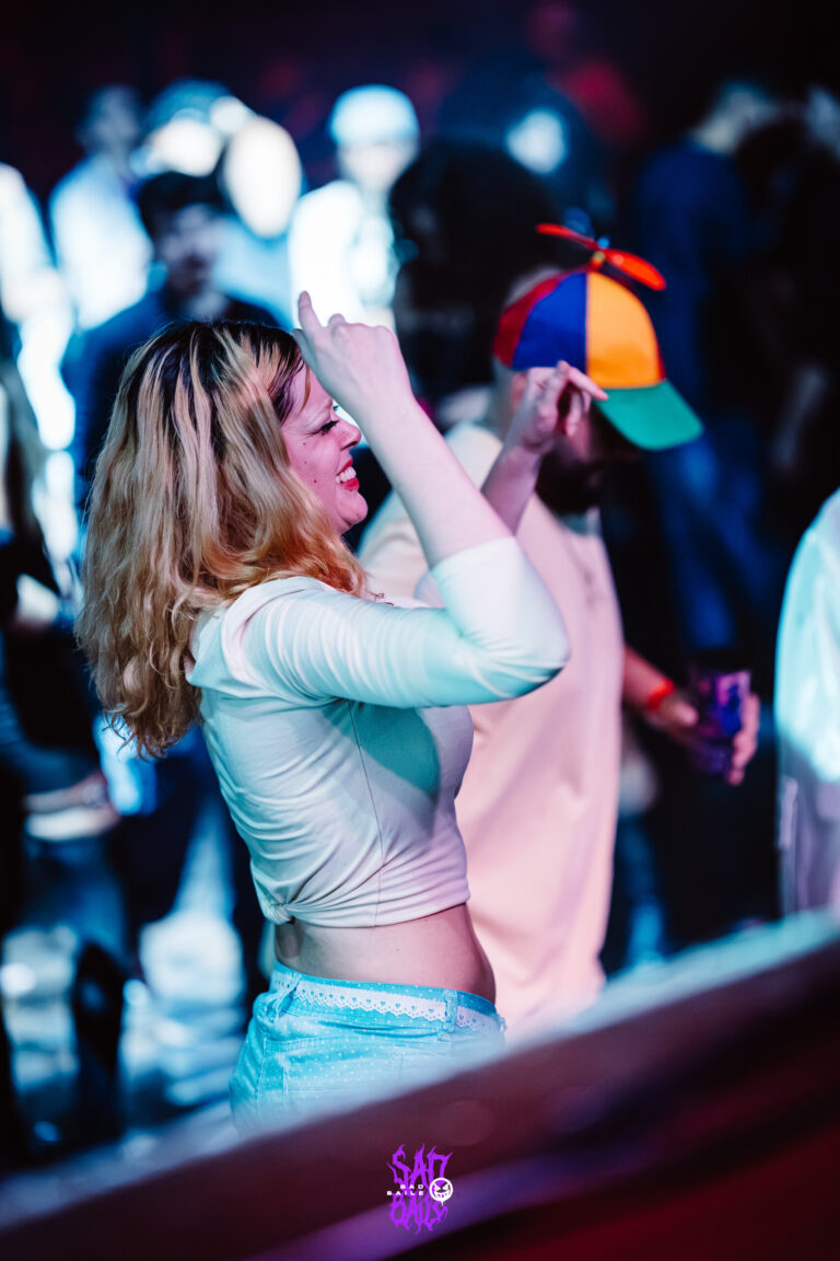 Garota de cabelo loiro dança ao lado de rapaz de chapéu de hélice — Sad Baile Joker, Halloween em São Paulo, 17/10/2026