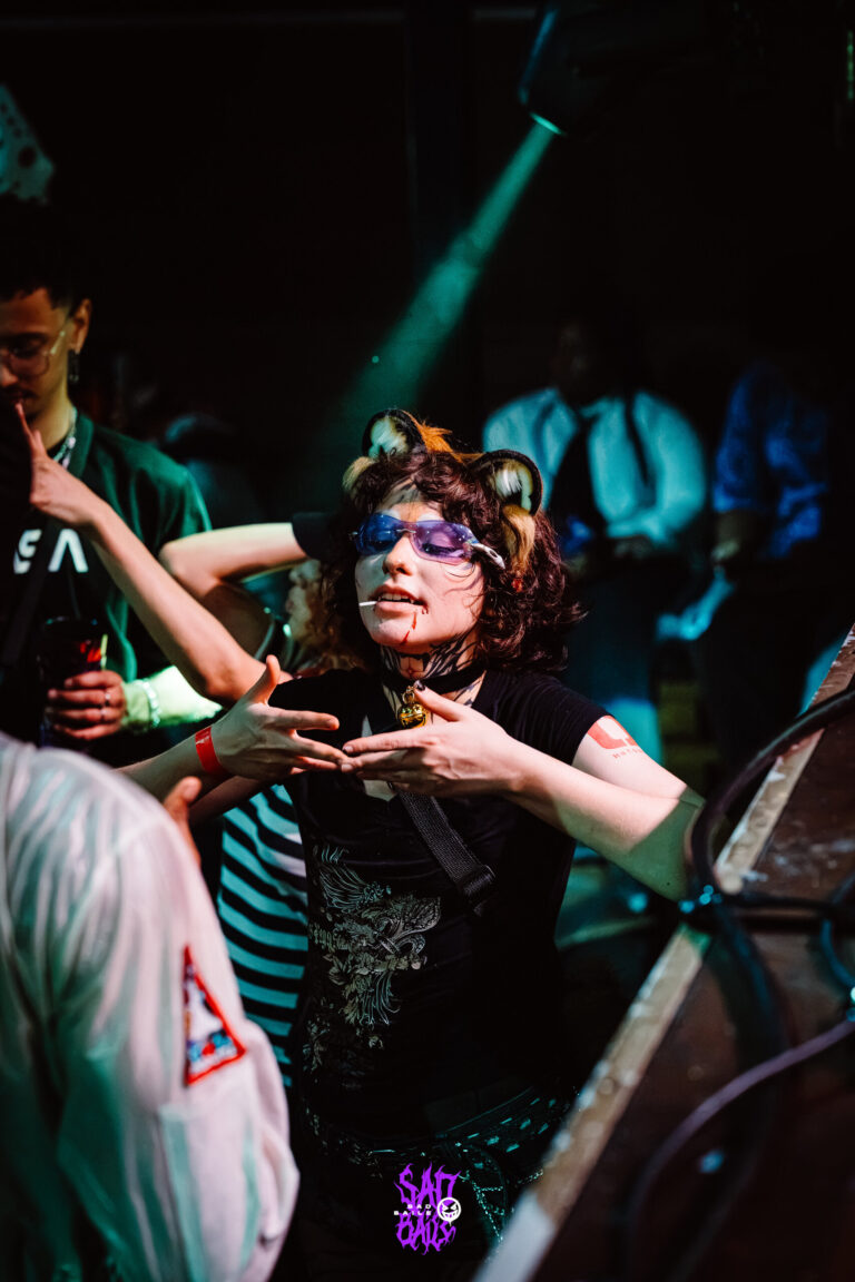 Garota de óculos escuros dança sob luz verde — Sad Baile Joker, Halloween em São Paulo, 17/10/2026