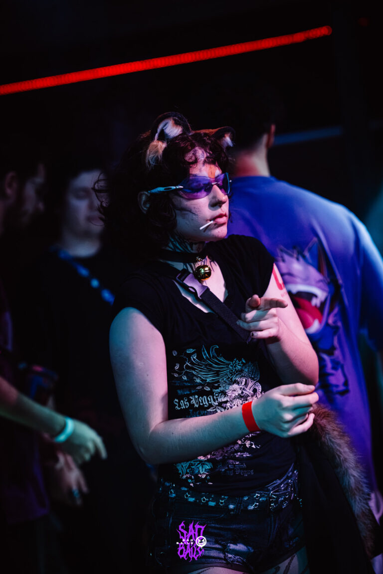 Garota de óculos de sol dança sob luz azul — Sad Baile Joker, Halloween em São Paulo, 17/10/2026